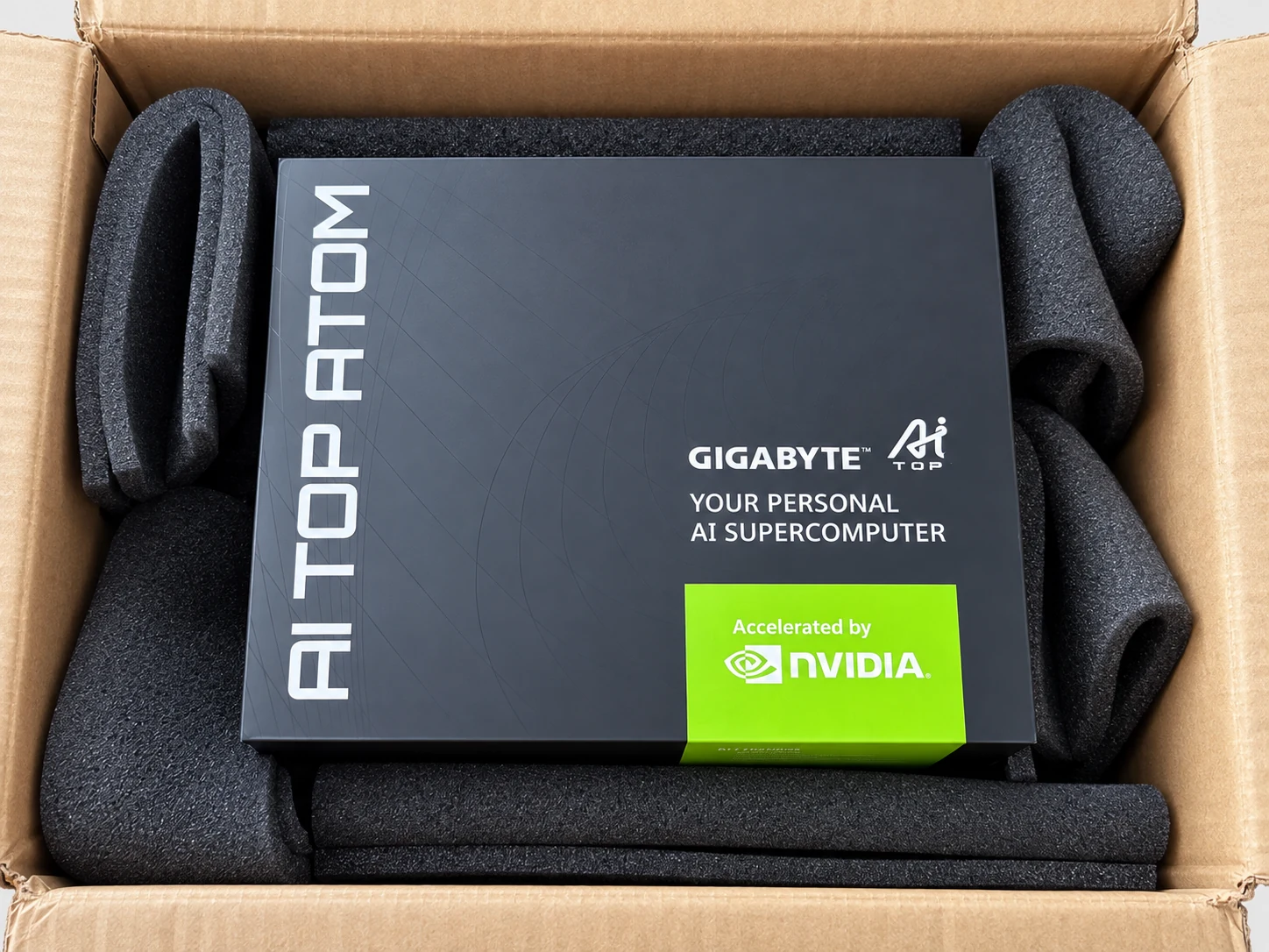 Scatola nera dell'AI TOP ATOM nel suo imballo di spedizione, bloccata dalla schiuma, con le diciture GIGABYTE AI TOP e Accelerated by NVIDIA.
