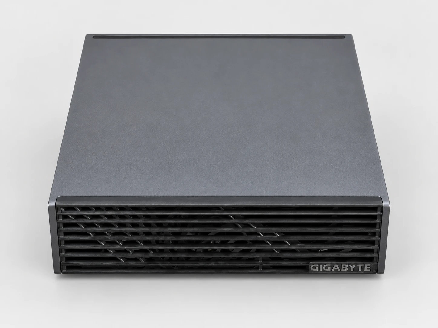 L'AI TOP ATOM vista dall'alto e di fronte: coperchio liscio grigio antracite, frontale a lamelle e logo GIGABYTE.
